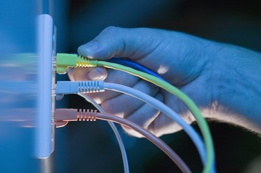 Hand plugging ethernet cable into wall socket