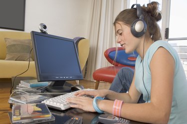 Young woman wearing headphones and using computer