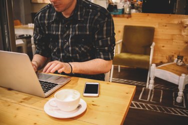 Young man sitting in a coffee shop using laptop