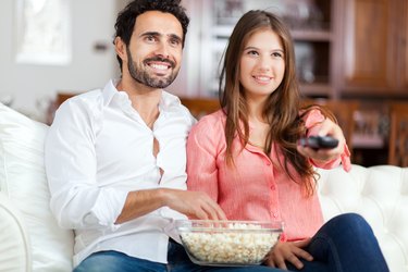 Young couple watching tv and eating pop-corn
