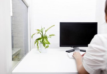 Rear view of young businesswoman using computer at desk