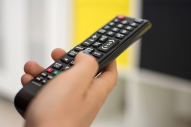 Close up of a hand holding a television remote control.