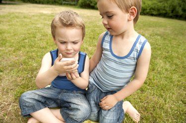 Twin brothers looking at cell phone in park