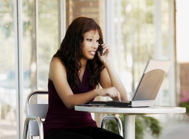 Woman talking on cell phone with laptop