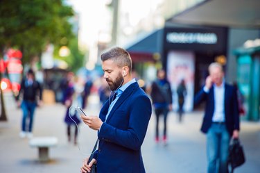 Manager with smartphone listening music outside in the street