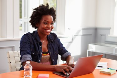 Young black woman using laptop computer at a desk, close-up