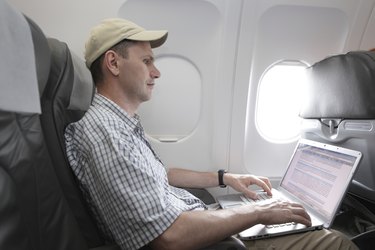 Passenger with laptop in airplane