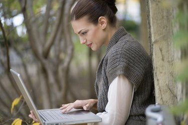 Side view of young businesswoman using laptop in yard