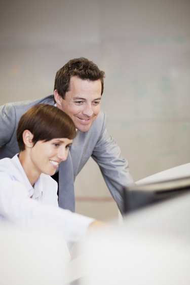 Smiling businessman and businesswoman using computer