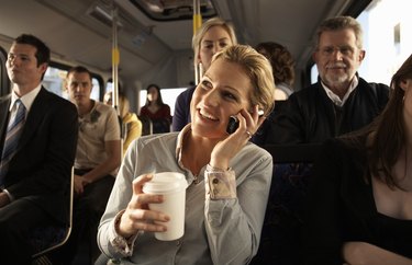 Woman using mobile phone on bus, smiling