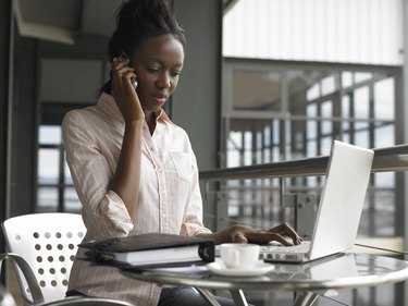 Young businesswoman sitting using laptop and mobile phone