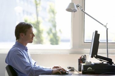 Man sitting at desk using computer, side view