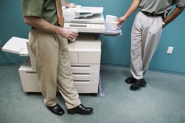 Low section view of two businessmen standing at a photocopying machine