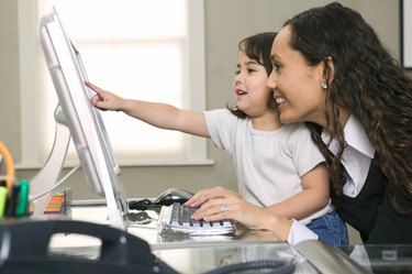 lifestyle shot of a young adult mother as she and her daughter use her computer
