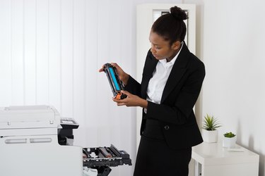 Businesswoman Fixing Cartridge In Office