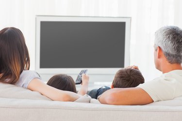 Family sitting on sofa watching television together