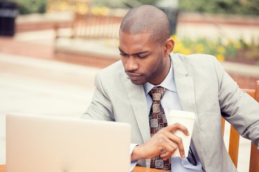 Handsome thoughtful business man working on laptop outdoors