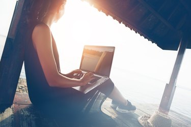 Woman working with laptop on the beach