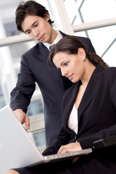 Side profile of a businesswoman and a businessman looking at a laptop