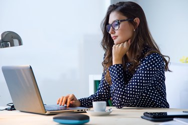 Beautiful young woman working with laptop in her office.