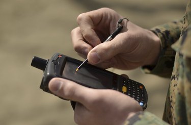 U.S. Marine using GPS capabilities on a handheld device to check his location.