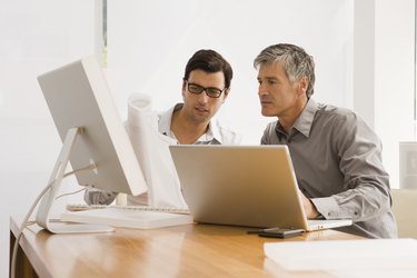 Two businessmen discussing a blueprint in an office