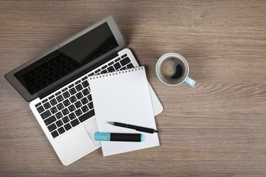 Blank notepad over laptop and coffee cup