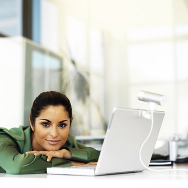 portrait of a young woman leaning forward on the table with a laptop in front of her