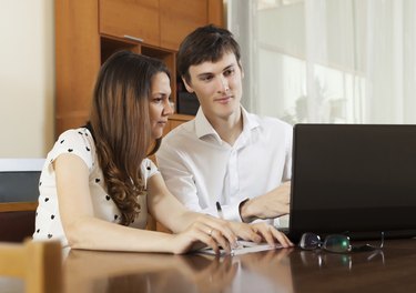 Young couple looking financial documents in laptop