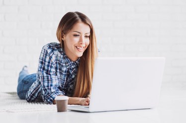 Happy student girl using laptop at home