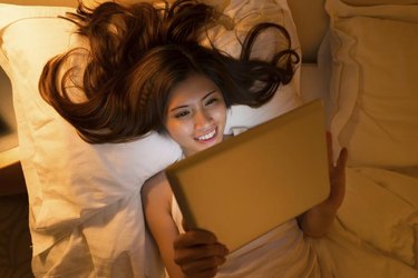 Young woman using some application on her digital tablet at night, view from above