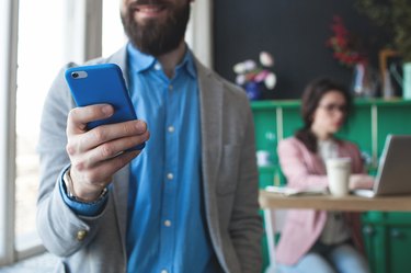 A bearded business man in glass looking at his phone