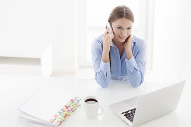 Woman using cell phone and looking at computer