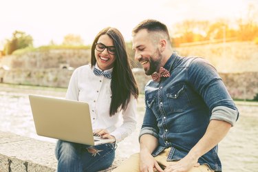 Couple of hipster friends using laptop in the city