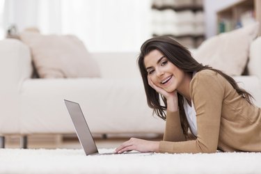 Smiling woman relaxing at home with laptop