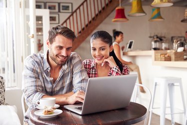 Young couple using laptop in a cafe smiling