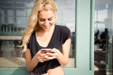 Pretty young woman sends a text message from her phone.