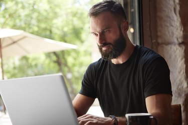 Concentrated Bearded Man Wearing Black Tshirt Working Laptop Wood Table