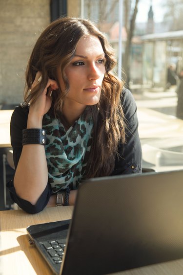 Beautiful Brunette Working on Laptop in a City Cafe