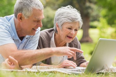 Smiling senior couple using laptop at park