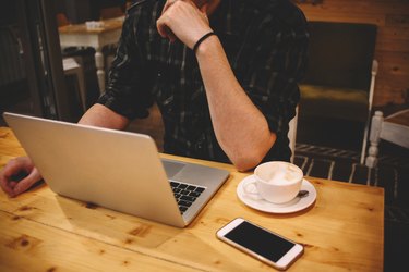 Young man sitting in a coffee shop using laptop