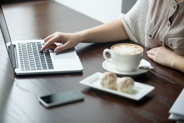 Close-up of female hands working on laptop in cafe