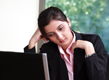 A worried businesswoman looking at laptop, partial view