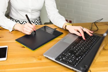 Close-up of designer using graphics tablet while working with