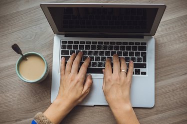 Laptop and coffee cup in girl's hands