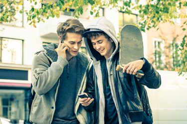 Young hipster best friends brothers having fun with smartphone
