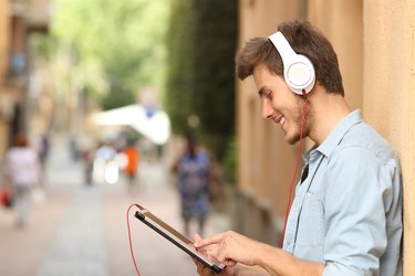 Man using a tablet with headphones on the street