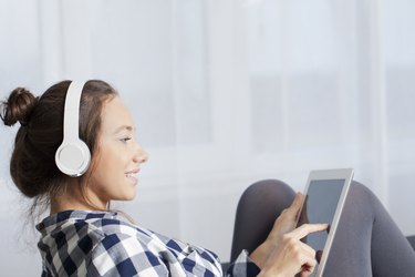 Woman With Headphones Listens Music On Tablet PC