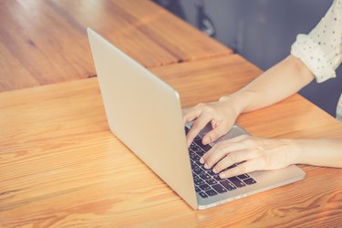 Hand woman typing key pad of laptop.