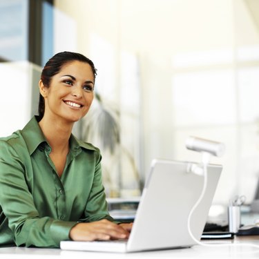 young woman smiling while using a laptop